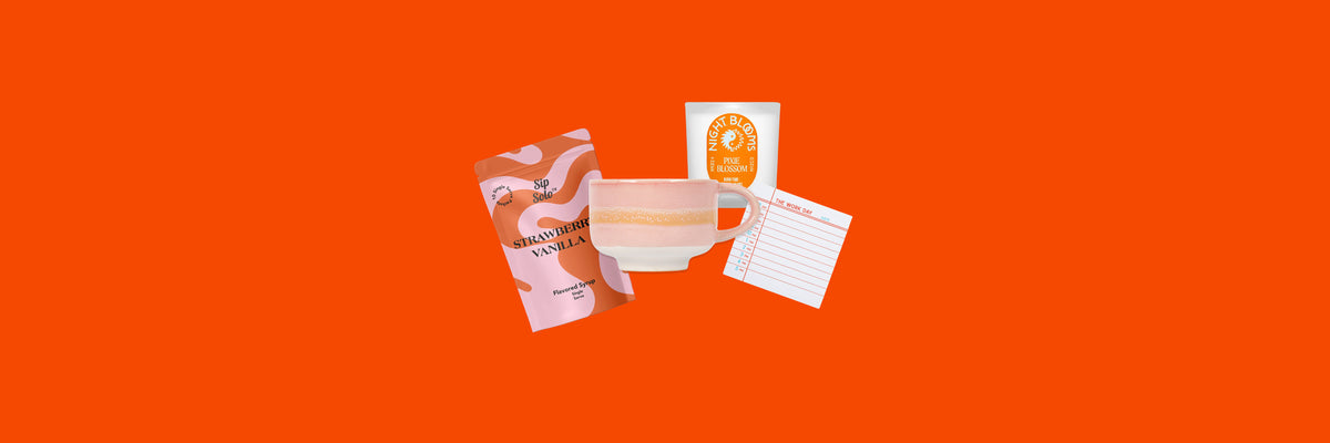 Syrup pouch, pink glazed mug, orange-label candle and a work day notepad on an orange background