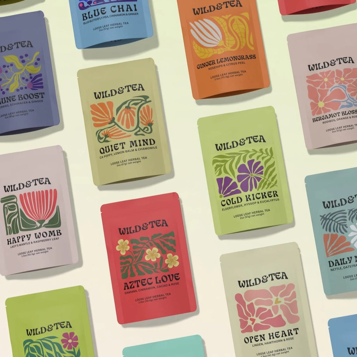 A flat-lay arrangement of multiple Wild & Tea tea pouches in different colors, each with a distinct illustrated design and flavor names.